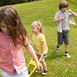 Three Children two girls and one boy who are a mixed of deaf and hard of hearings playing in the grss