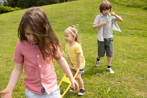 Three Children two girls and one boy who are a mixed of deaf and hard of hearings playing in the grss