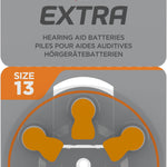 Packaging of Rayovac Extra hearing aid batteries, Size 13, 6-pack. The front of the package is gray with orange accents, featuring the Rayovac Extra logo with a red and black lightning bolt. A wheel of six batteries, marked with orange tabs, is visible through a transparent section.