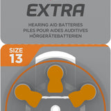 Packaging of Rayovac Extra hearing aid batteries, Size 13, 6-pack. The front of the package is gray with orange accents, featuring the Rayovac Extra logo with a red and black lightning bolt. A wheel of six batteries, marked with orange tabs, is visible through a transparent section.