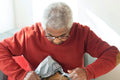 Person in a red sweater opening a package with tinfoil on a couch.